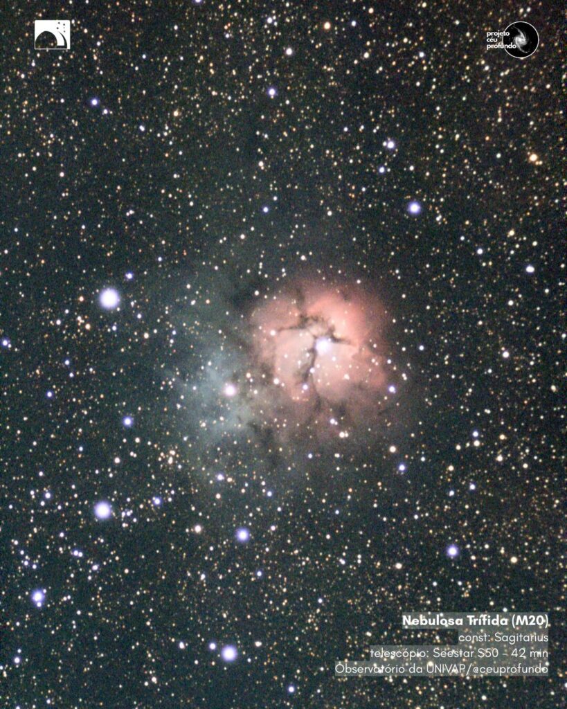 Imagem da Nebulosa M20, também conhecida como Nebulosa de Trífida, localizada na constelação de sagitário. No centro da imagem, a nebulosa se destaca com sua coloração rosa, à direita, e azul, à esquerda. Ao fundo escuro, há uma grande quantidade de estrelas alaranjadas e azuladas espalhadas. No canto inferior direito, lê-se: “Nebulosa Trífida (M20), const: Sagittarius, telescópio: Seestar S50 – 42 min, Observatório da UNIVAP / @ceuprofundo”. Logotipos do observatório e do Projeto Céu Profundo estão presentes nos cantos superior esquerdo e direito.