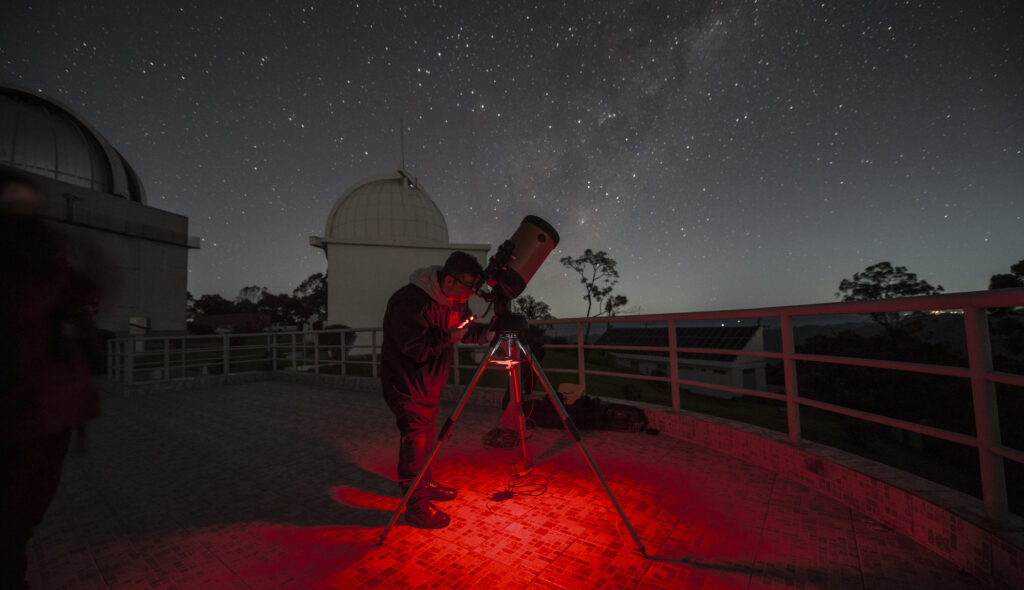 Telescópio no Observatório da UNIVAP sob iluminação vermelha.